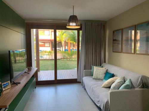 uma sala de estar com um sofá e uma televisão em Apartamento luxo Barra Grande Península de Maraú em Maraú