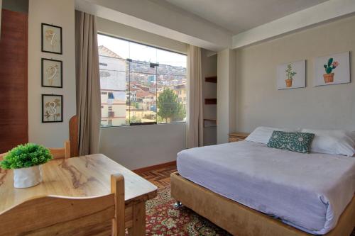 a bedroom with a bed and a table and a window at Sunny 6 bedroom house with private garden & rooftop in Cusco