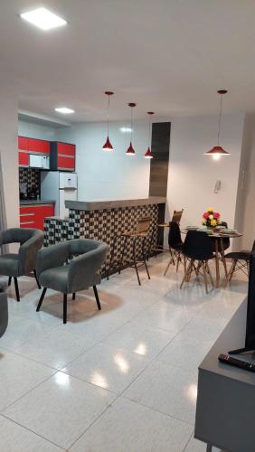 a living room with chairs and a table and a kitchen at Apartamento mobiliado no centro de paulo afonso in Paulo Afonso