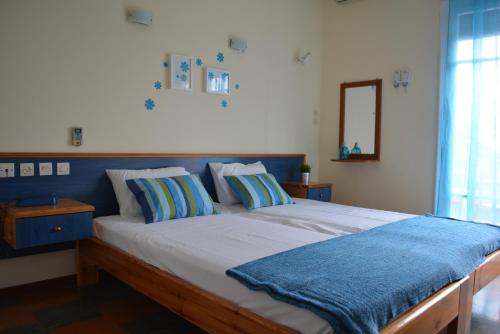a bedroom with a large bed with a blue headboard at Dimitra Hotel in Kamena Vourla