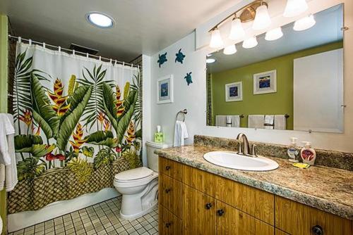 a bathroom with a sink and a toilet and a mirror at Kona Makai 3-302 in Kailua-Kona