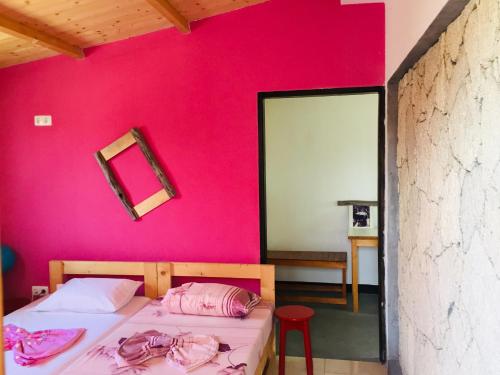 a bedroom with a pink wall with a bed and a mirror at Pedra de Rala in Porto Novo
