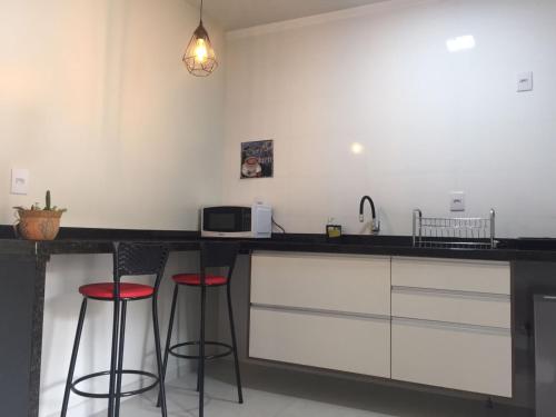 a kitchen with two bar stools and a microwave at Flat Santa Cruz do Sul in Santa Cruz do Sul