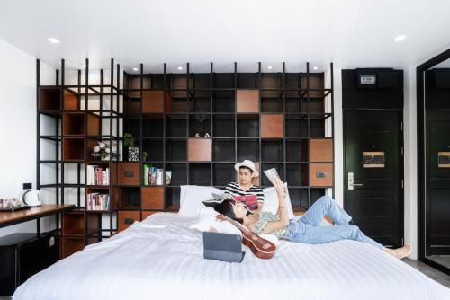 two people laying on a bed with a guitar at Book a Bed Poshtel - SHA Plus in Phuket Town