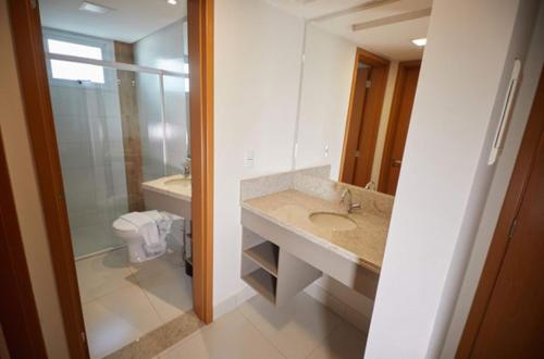 a bathroom with a sink and a toilet and a mirror at Apartamento Resort do Lago in Caldas Novas