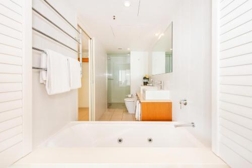 Baño blanco con bañera y lavamanos en Lanai Riverside Apartments, en Mackay