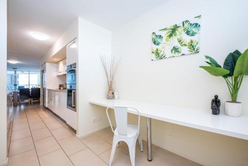 a kitchen and dining room with a white counter and chairs at Lanai Riverside Apartments in Mackay