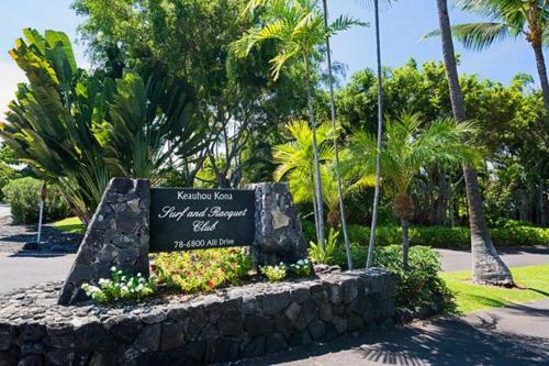 a sign in a park with flowers and palm trees at Keauhou Kona Surf & Racquet Club #6-104 in Kailua-Kona