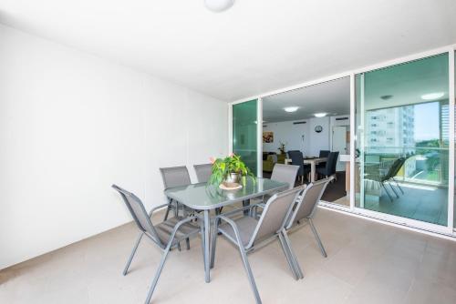 a dining room with a glass table and chairs at Lanai Riverside Apartments in Mackay