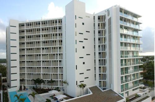 a white building with palm trees in front of it at Lanai Riverside Apartments in Mackay
