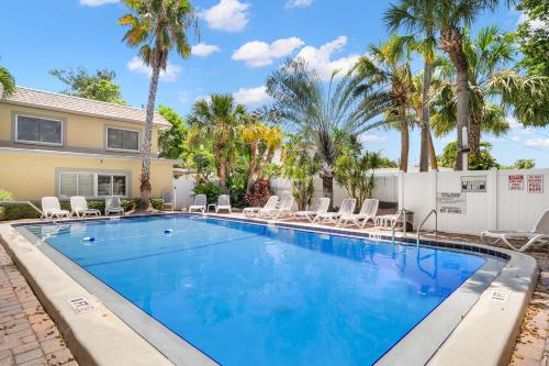 a swimming pool with chairs and palm trees at Waves 18 in St Pete Beach