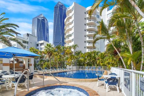a swimming pool with tables and chairs and buildings at Surf Parade Resort in Gold Coast