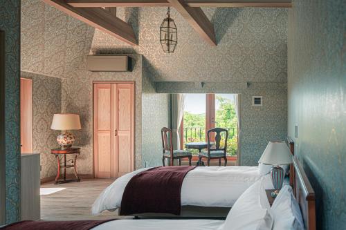 a bedroom with a bed and a table and chairs at Aubergeフレンチの森 in Kusumoto