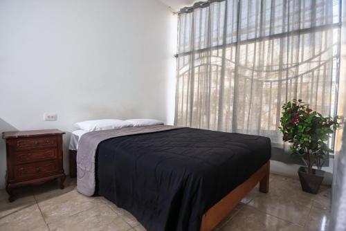 a bedroom with a bed with a black blanket and a window at Gran Imperial Avenida in Tumbes