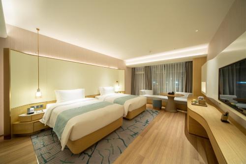 a hotel room with two beds and a flat screen tv at Wyndham Garden Jinjiang in Jinjiang