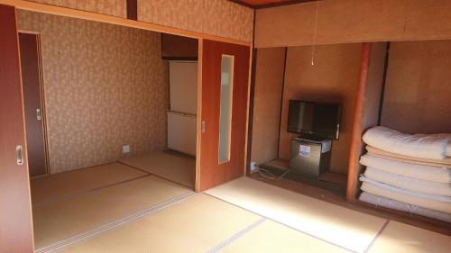 a room with a tv and a bed and towels at Guesthouse Kumano in Tanabe
