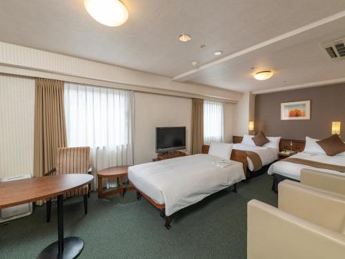 a hotel room with two beds and a table at Alpico Plaza Hotel in Matsumoto