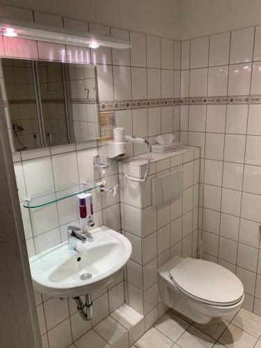 a white bathroom with a toilet and a sink at Hotel Goldene Krone in Goslar