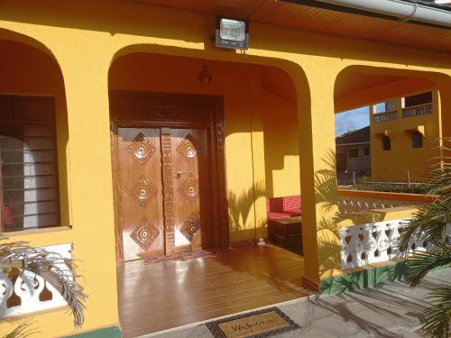 a yellow house with a door with a wooden floor at Golden Duranta Villas in Ukunda