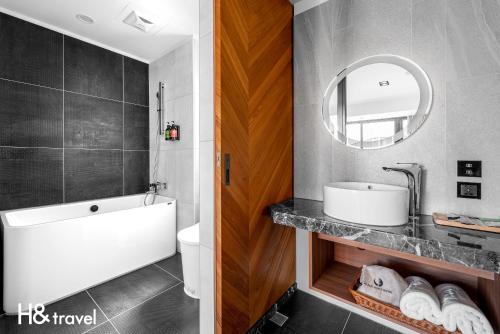 a bathroom with a tub and a sink and a mirror at Black Horn B&B in Hengchun