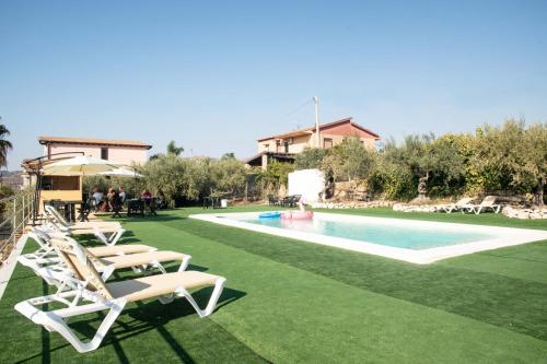 una piscina con sillas de césped y una casa en B&B Villa Kairos, en Agrigento