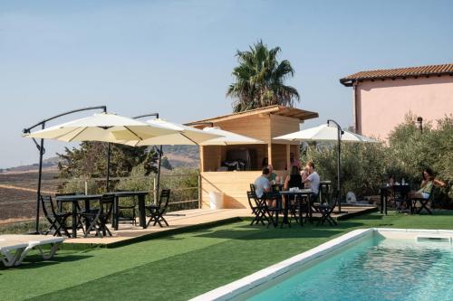 アグリジェントにあるB&B Villa Kairosのスイミングプールの隣にパティオ(テーブル、パラソル付)