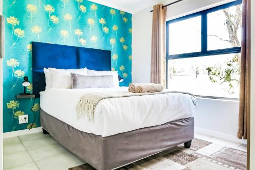a bedroom with a large bed with a blue wall at Green Park Haven 1 in Pretoria