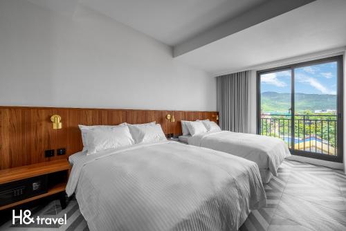 two beds in a hotel room with a large window at Black Horn B&B in Hengchun