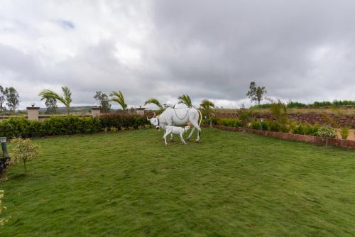 a statue of a cow standing in a field at Blizzard Resort in Panchgani