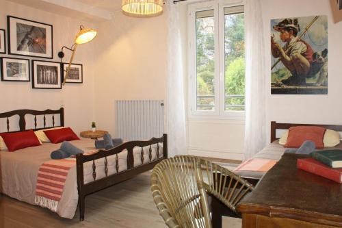 1 dormitorio con 2 camas, mesa y ventana en Hôtel des Bateliers en La Malène