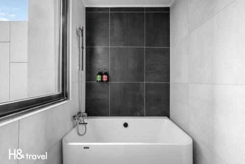 a bathroom with a white bath tub and a toilet at Black Horn B&B in Hengchun