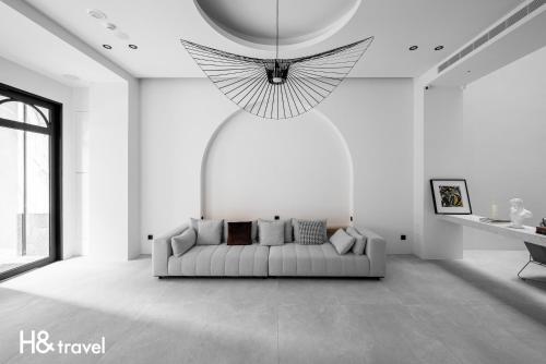 a white living room with a couch and a chandelier at Black Horn B&B in Hengchun