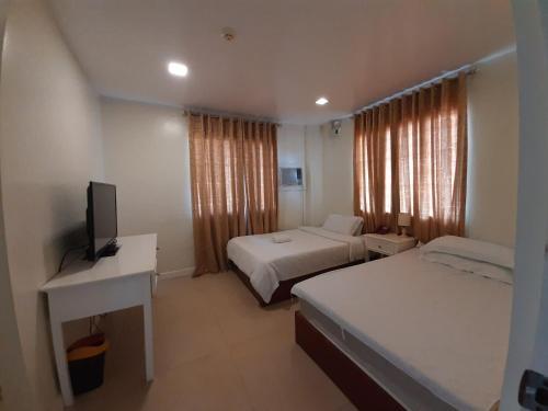 a bedroom with two beds and a desk and a television at RedDoorz at Balatas Magsaysay Road Naga City in Naga