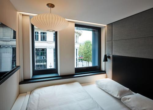 een slaapkamer met een bed en 2 ramen bij citizenM Paris Champs-Élysées in Parijs