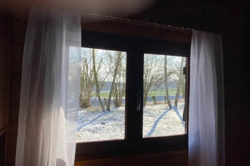 a window with a view of a snow covered yard at Maison 2 chambres proche Dijon chalet niché dans la nature in Saint-Maurice-sur-Vingeanne