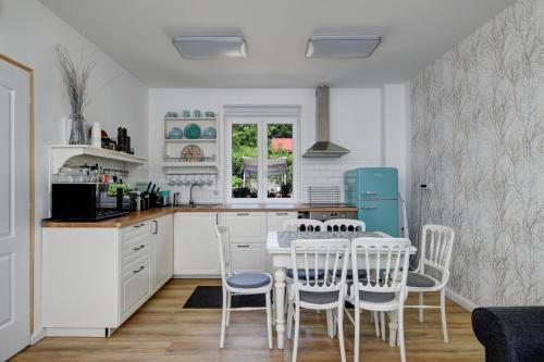 a kitchen with white cabinets and a table and chairs at Virágos Vendégház a Dunakanyarban, privát kerttel in Nagymaros