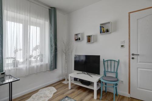 a living room with a tv and a chair at Virágos Vendégház a Dunakanyarban, privát kerttel in Nagymaros