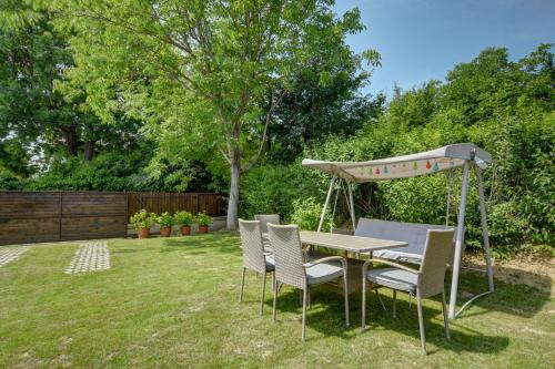 a picnic table with chairs and an umbrella in a yard at Virágos Vendégház a Dunakanyarban, privát kerttel in Nagymaros