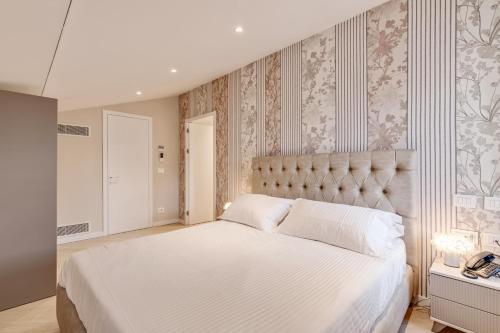 a bedroom with a large white bed and a phone at Oriana Homèl Udine in Udine