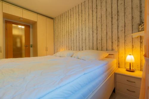 a bedroom with a large white bed and a lamp at Seepferdchen in Westerdeichstrich