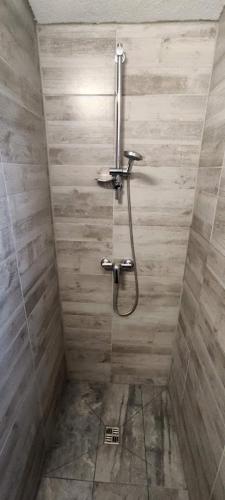 a shower in a bathroom with a wooden wall at Apartman Darko in Rogoznica