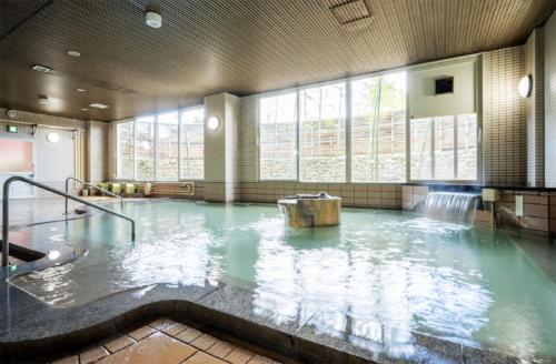 a large pool of water in a room with windows at フォレストコテージ奥州 in Oshu