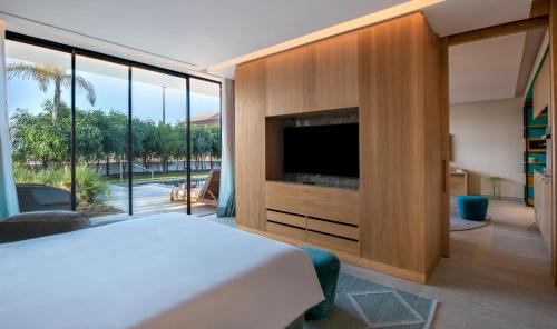 a bedroom with a bed and a tv and a large window at Hyatt Regency Taghazout in Taghazout