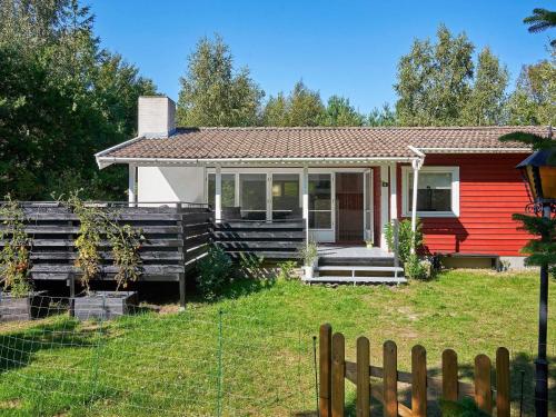 a red house with a fence in front of it at 4 person holiday home in Aakirkeby in Vester Sømarken