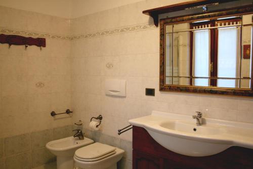 W łazience znajduje się umywalka, toaleta i lustro. w obiekcie La Robinera w mieście Magnano