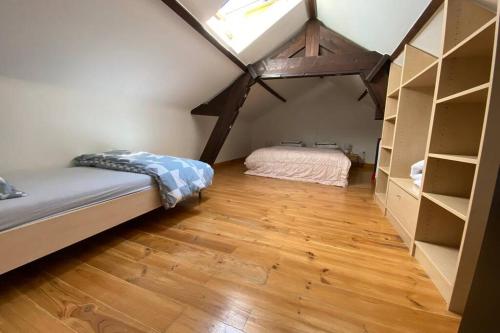 - une chambre mansardée avec un lit et une étagère dans l'établissement La Petite Maison, à Bienne-lez-Happart