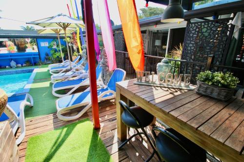 a deck with chairs and a table and a pool at Hideaway Noosa Men Only Beach Resort in Peregian Beach