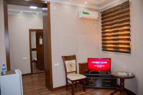 a living room with a tv and a table and chair at Euro Asia Hotel in Samarkand