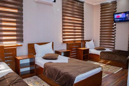 a room with three beds and a flat screen tv at Euro Asia Hotel in Samarkand