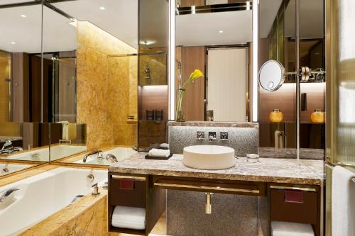 
a bathroom with a sink, mirror, and bathtub at Four Seasons Hotel Hong Kong in Hong Kong
